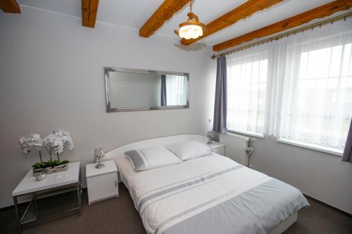 a white bedroom with a bed and windows at Noclegi Cristal in Malbork