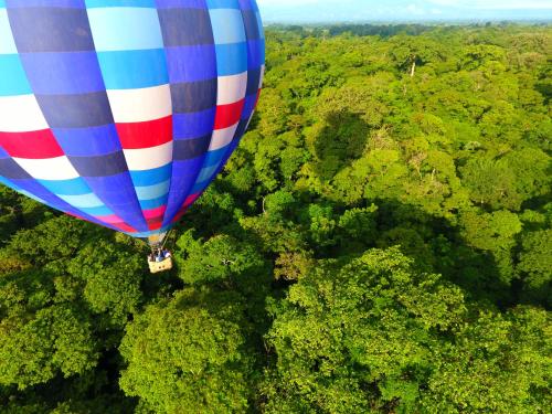 a hot air balloon flying over a forest at La Finca Lodge in Fortuna