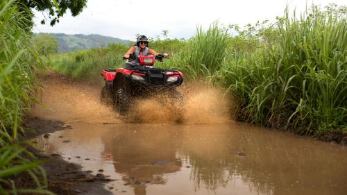 a man riding a quad bike through a muddy field at La Finca Lodge in Fortuna