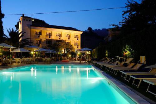 a large swimming pool with chairs and a building at Hotel Caserta Antica in Caserta