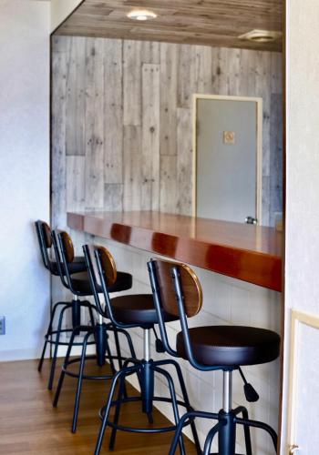 a bar with four chairs and a counter with a mirror at Guesthouse All you need - All rooms have an ocean view! in Shimoda