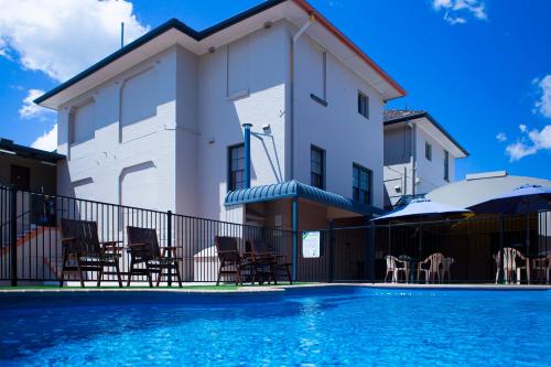 a house with a swimming pool in front of a building at Lismore City Motor Inn in Lismore