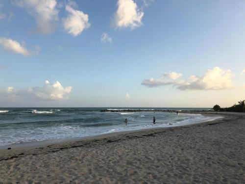 a beach with people standing in the water at La Gaviota A3 in Juan Dolio