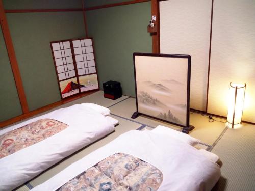 2 camas en una habitación con una pintura en el suelo en Kyoto Villa Kotone, en Kioto