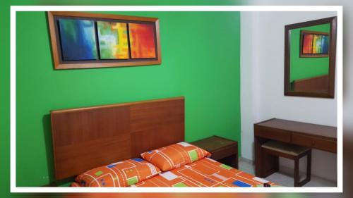 a bedroom with a bed and a green wall at HOTEL CASA BLANCA BUGA in Buga