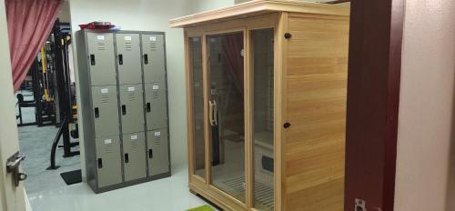 a wooden cabinet with a glass door next to lockers at โฮมสเตย์ เมืองไทยฟิตเนส อารีนา in Ban Bo Nam