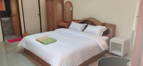 a bedroom with a white bed with a green towel on it at โฮมสเตย์ เมืองไทยฟิตเนส อารีนา in Ban Bo Nam