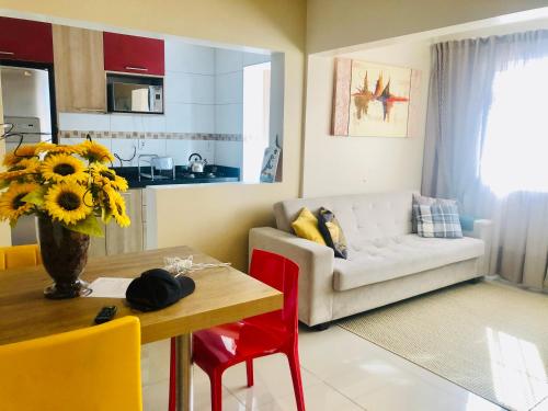 uma sala de estar com um sofá e uma mesa com um vaso de flores em Flat Blumenau Vila Nova em Blumenau
