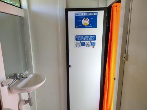 un baño con lavabo y un cartel en la puerta en Glamping - Calochorno, en Alcalá