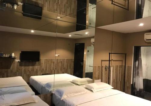 a bedroom with two beds and a mirror at Time Hotel in Seremban