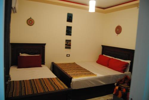 2 camas en una habitación con almohadas rojas en Badr Deluxe Apartments - Families Only en El Alamein