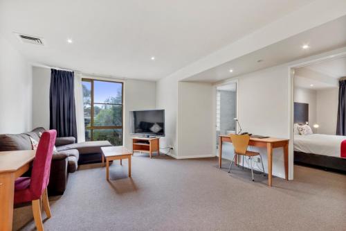 a hotel room with a bedroom and a bed and a desk at Knox International Hotel and Apartments in Wantirna