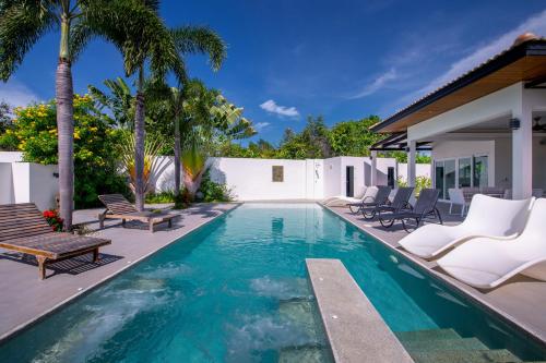 a swimming pool with chairs and a house at Orchid Paradise Homes Villa in Hua Hin