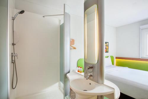 a bathroom with a shower and a toilet and a sink at Ibis Budget Semarang Tendean - CHSE Certified in Semarang