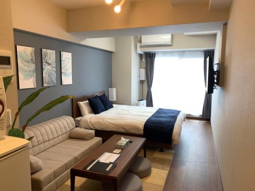 um quarto com uma cama e uma sala de estar com um sofá em @RLiS_house新大阪北 em Osaka