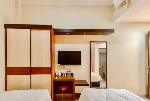 um quarto com uma cama, uma televisão e um espelho em RedDoorz Syariah Plus near Cirebon Super Block Mall 2 em Cirebon