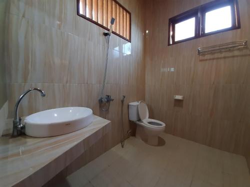 a bathroom with a sink and a toilet at Mas Cottages in Tuk Tuk