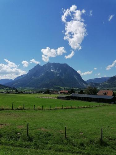 a field with a fence and mountains in the background at Amtmannhaus Ferienunterkunft in Irdning