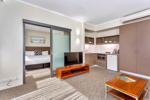 a living room with a television and a kitchen at New Haus by Hougoumont Hotel, former Bannister 22 in Fremantle