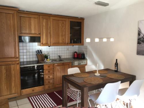 una cocina con armarios de madera, mesa y sillas en Apartment Allegra, en Küblis