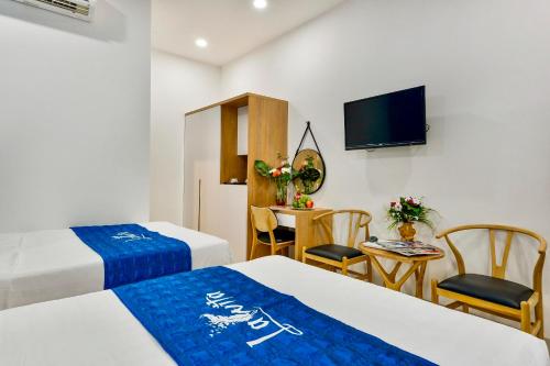 a hotel room with two beds and a small table at La Vita Hotel in Vung Tau