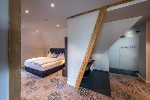 an attic bedroom with a bed and a staircase at Parkhotel Gunten – Beach & Spa in Gunten
