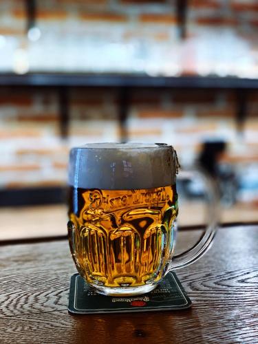 a glass of beer sitting on top of a table at Hotel & Apartments U Černého orla in Třebíč