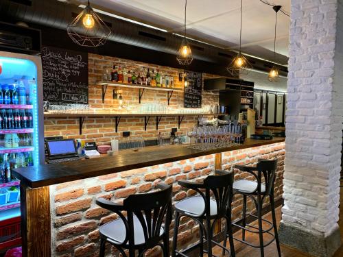 a bar with black chairs and a brick wall at Hotel & Apartments U Černého orla in Třebíč