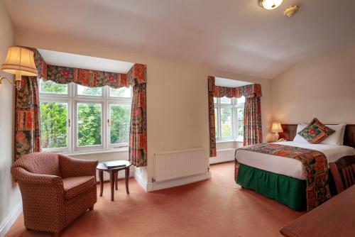 um quarto com uma cama, uma cadeira e janelas em Arundel House Hotel em Cambridge
