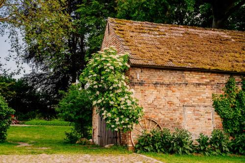 an old brick barn with a flowering plant on it at Gut Boltenhof in Fürstenberg-Havel