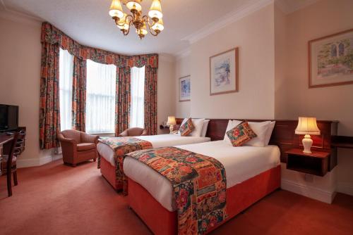 a hotel room with two beds and a chandelier at Arundel House Hotel in Cambridge