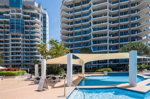 een zwembad met een tent en twee hoge gebouwen bij Oceana On Broadbeach in Gold Coast