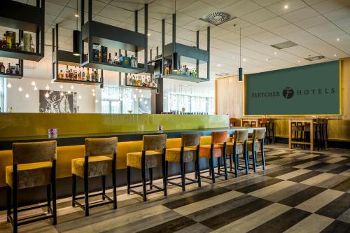a bar in a restaurant with a bunch of stools at Fletcher Wellness-Hotel Sittard in Sittard