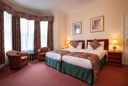 a hotel room with a bed and a chair at Ashley Hotel in Cambridge