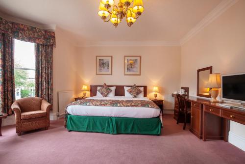 a bedroom with a bed and a desk and a television at Ashley Hotel in Cambridge