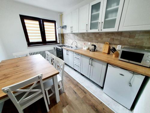 cocina con armarios blancos y mesa de madera en U Mlynára, en Ružomberok