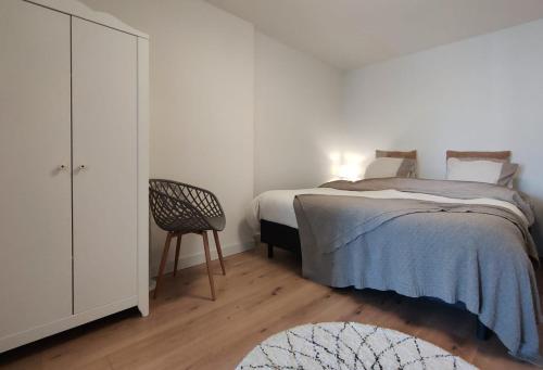 a white bedroom with a bed and a chair at Cosy Tiny House 5 min walk Keukenhof included entrance keukenhof in Lisse