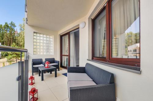 a balcony with chairs and a table and windows at Bursztynowe Osiedle Jantar, Sun & Snow in Jantar