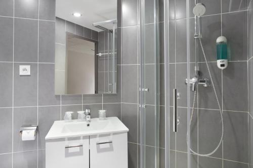 La salle de bains est pourvue d'une douche et d'un lavabo. dans l'établissement Lille City Hotel, à Lille