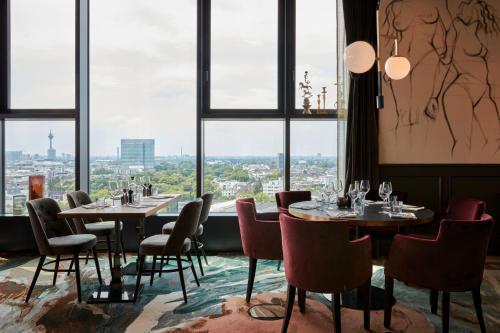 
a dining room with a large window overlooking a city at 25hours Hotel Das Tour in Düsseldorf
