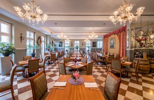 a restaurant with tables and chairs and chandeliers at Sebnitzer Hof by STEIGER Hotels in Bad Schandau