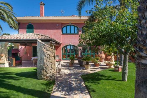 a large red house with a palm tree in front of it at Villa Flumini in Flumini di Quartu