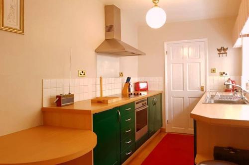 a kitchen with green cabinets and a sink at No 6 The Square Tearooms & Accommodation in Buxton