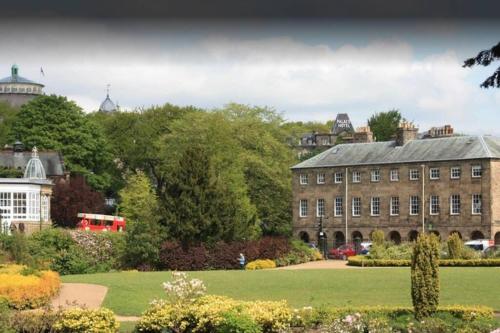 a large building with a green lawn in front of it at No 6 The Square Tearooms & Accommodation in Buxton