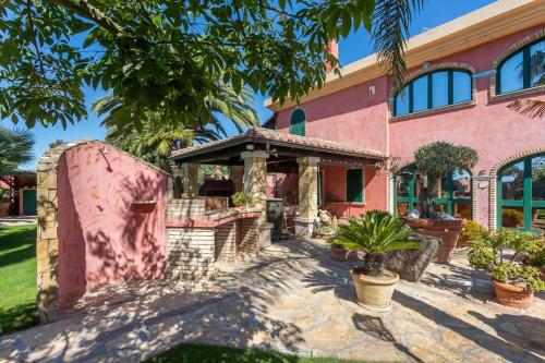a pink house with a gazebo at Villa Flumini in Flumini di Quartu
