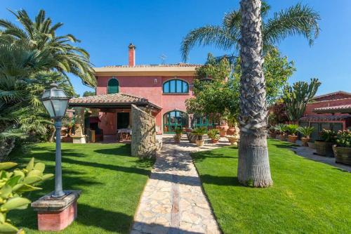 a house with a palm tree in the yard at Villa Flumini in Flumini di Quartu