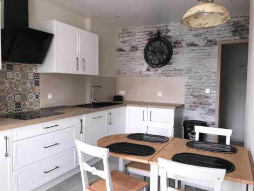une cuisine avec une table en bois et une horloge au mur dans l'établissement Le coin de Fréderic, à Colmar