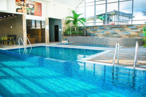 a swimming pool with blue water in a building at Radailiu Dvaras - Dinosaur Park in Radailiai