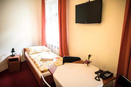 Habitación con cama, mesa y TV. en Żaczek Hotele Studenckie, en Cracovia
