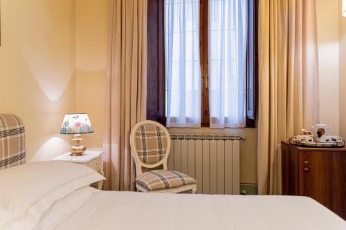 a bedroom with a bed and a chair and a window at Casa Uffizi XIII Century Tower House Boutique Hotel in Florence